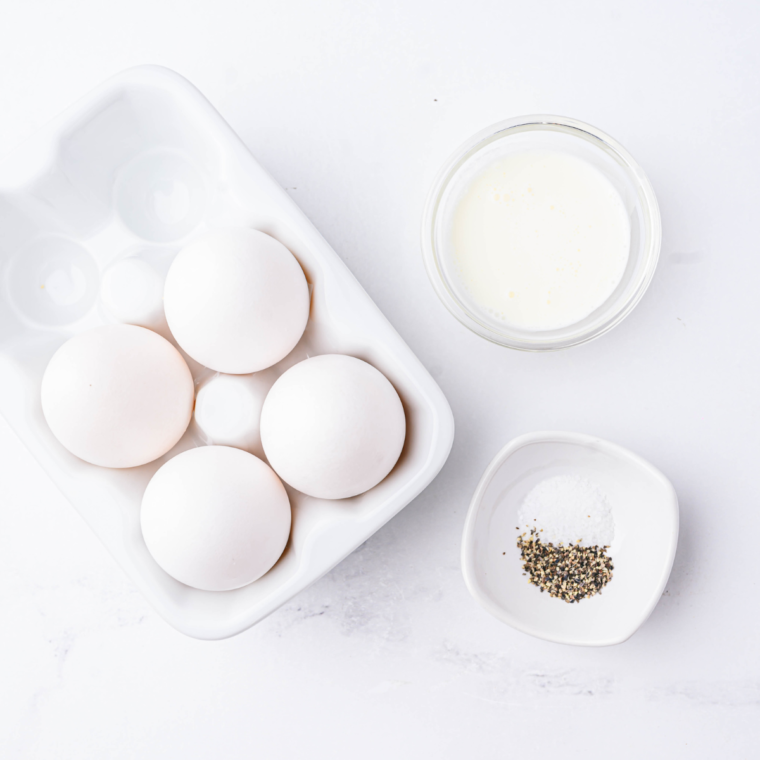 Show more
1:30 PM
Ingredients laid out on a marble countertop for an air fryer ham and cheese omelette — three large eggs, small bowl of milk, diced cooked ham, shredded Swiss cheese, chopped chives, kosher salt, black pepper, and a 6-inch round pan