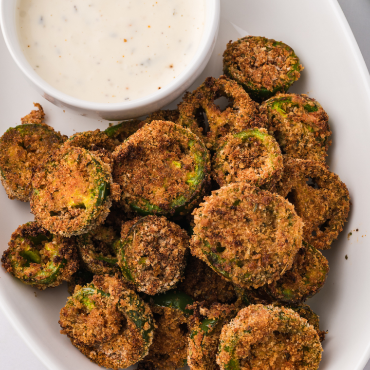 Golden, crispy air-fried jalapeño slices served on a plate, perfect for snacking or as a spicy topping.