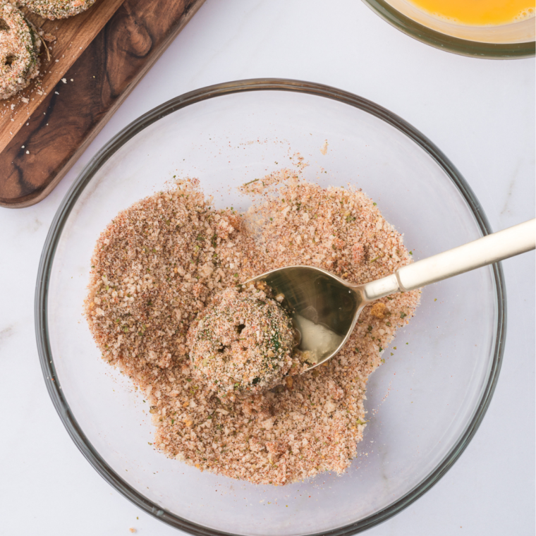 Coating jalapeno slices by dipping them in egg and seasoned breadcrumbs.