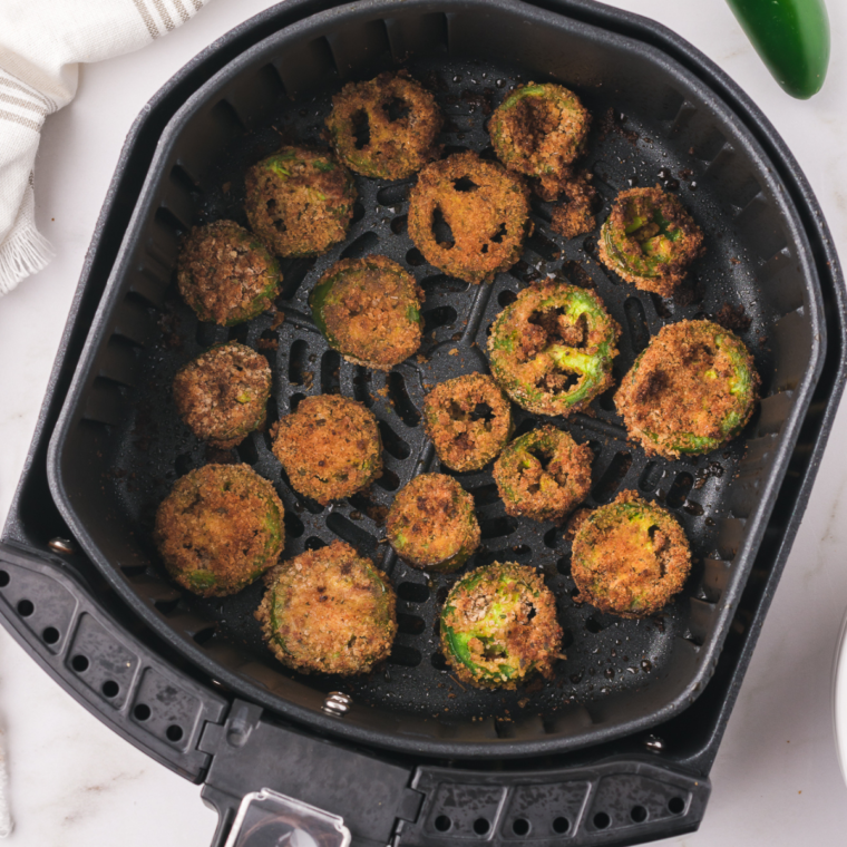 Crispy, golden air-fried jalapeño slices served on a plate with a dipping sauce.