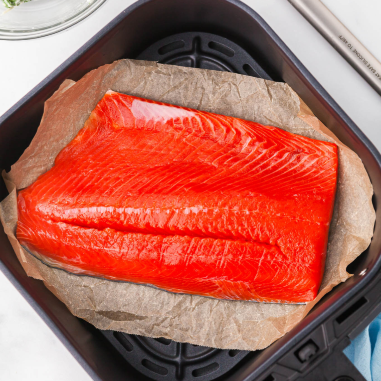 Seasoned sockeye salmon fillets arranged skin-side down in an air fryer basket