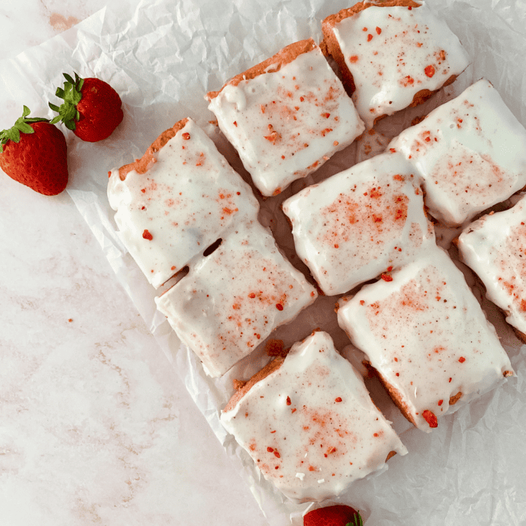 Close-up of a chewy strawberry blondie square topped with vanilla glaze