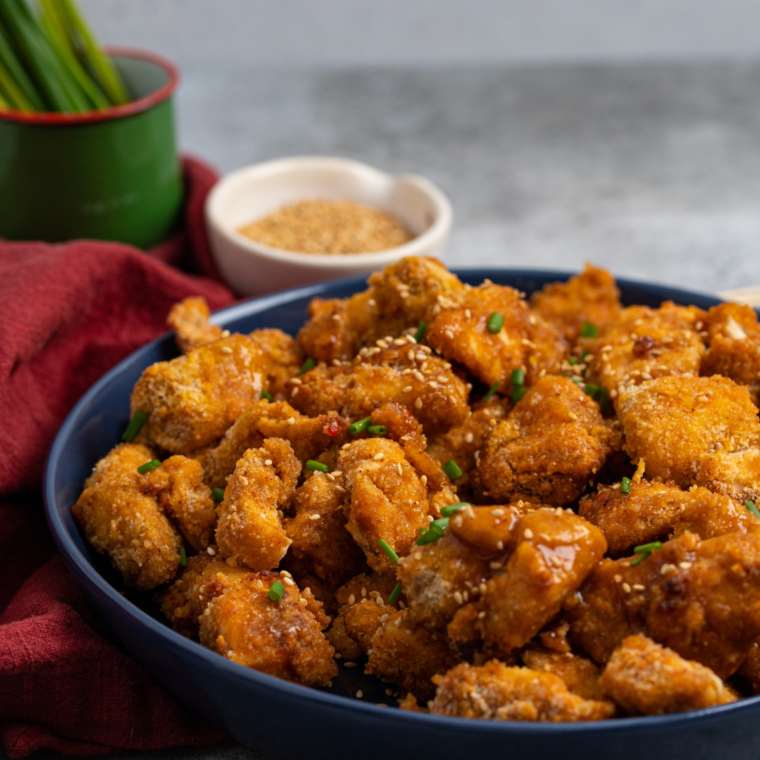 Plate of Air Fryer Sweet Chili Chicken Bites garnished with sesame seeds and green onions.