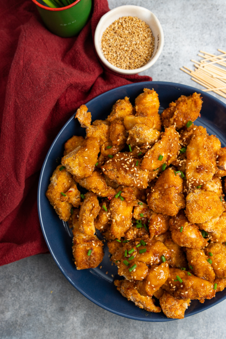 Air Fryer Sweet Chili Chicken Bites served on a plate, garnished with sesame seeds and green onions.
