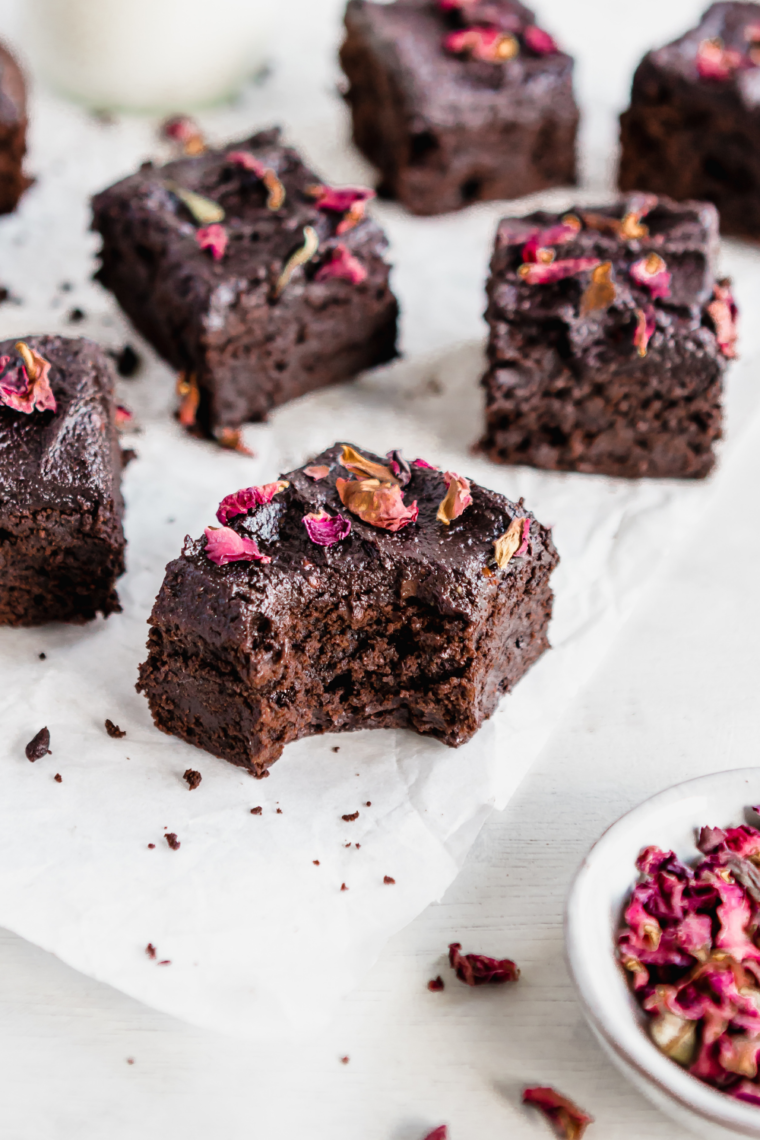 Close-up view of freshly baked zucchini brownies arranged on white parchment paper, highlighting their moist and fudgy texture.