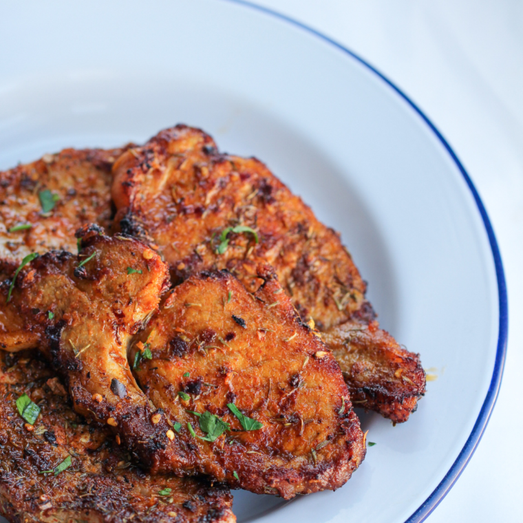 Juicy griddle pork chops with a browned crust resting on a wooden cutting board