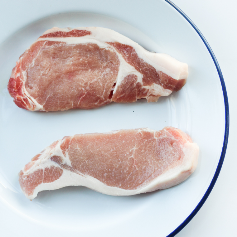 Raw pork chops rubbed with olive oil and seasoned before griddling