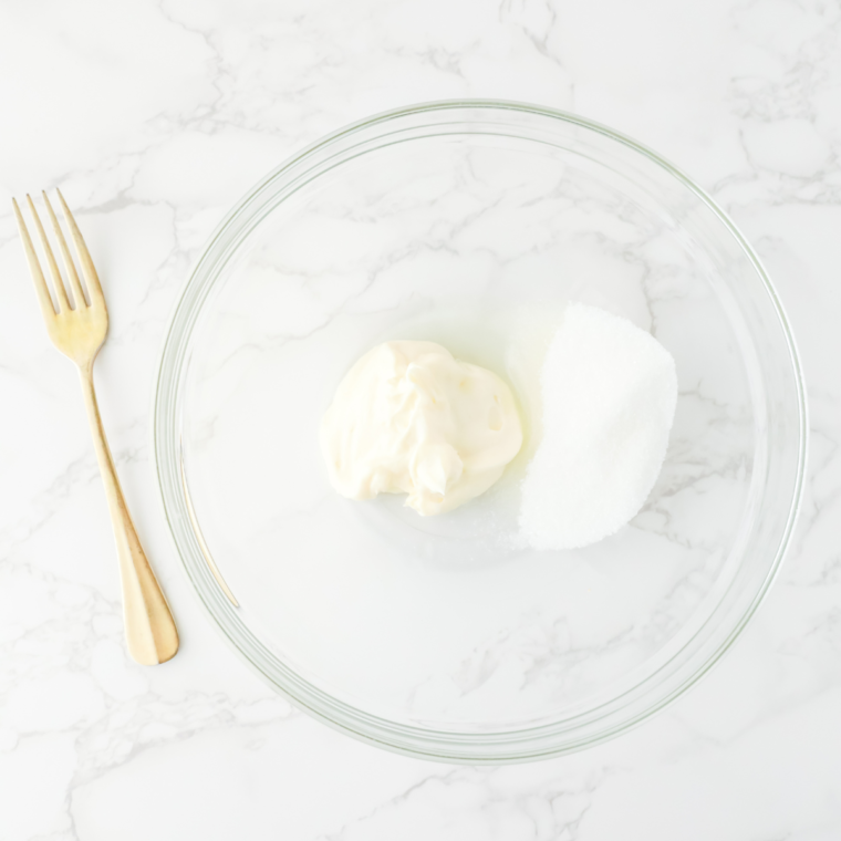 Combining vegan mayonnaise with shredded carrots and raisins for a creamy dressing.