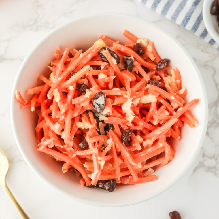 Serving a bowl of homemade Chick-fil-A carrot and raisin salad on a picnic table.