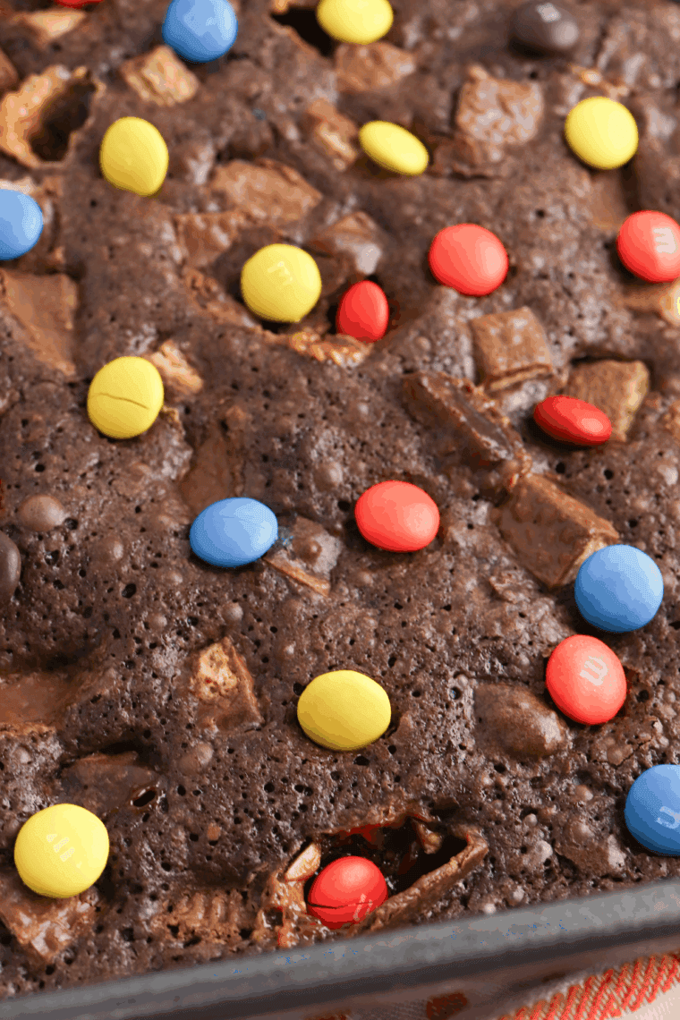 Fudgy brownies loaded with chopped leftover Halloween candy on a plate