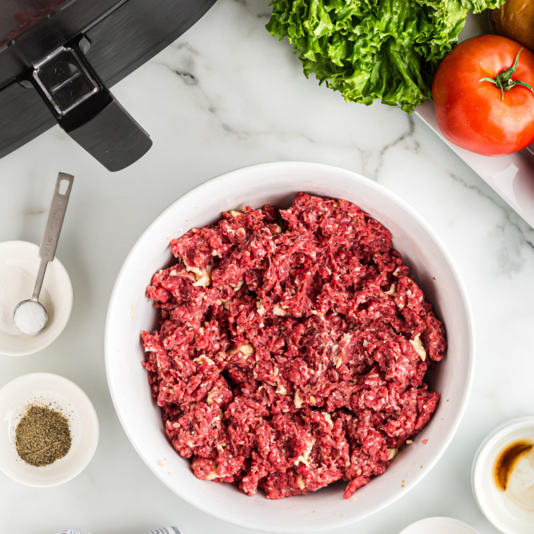 Placing burger patties in the Ninja Foodi air fryer basket.
