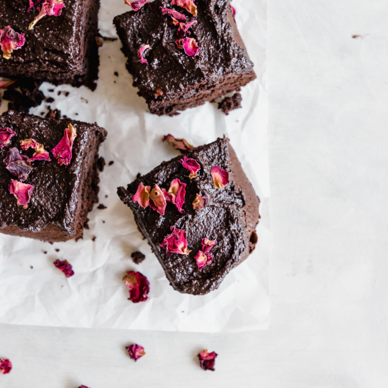 Close-up of air fryer zucchini brownies, highlighting their moist, fudgy texture with a glossy chocolate surface, and a few small chunks of zucchini visible within the brownies