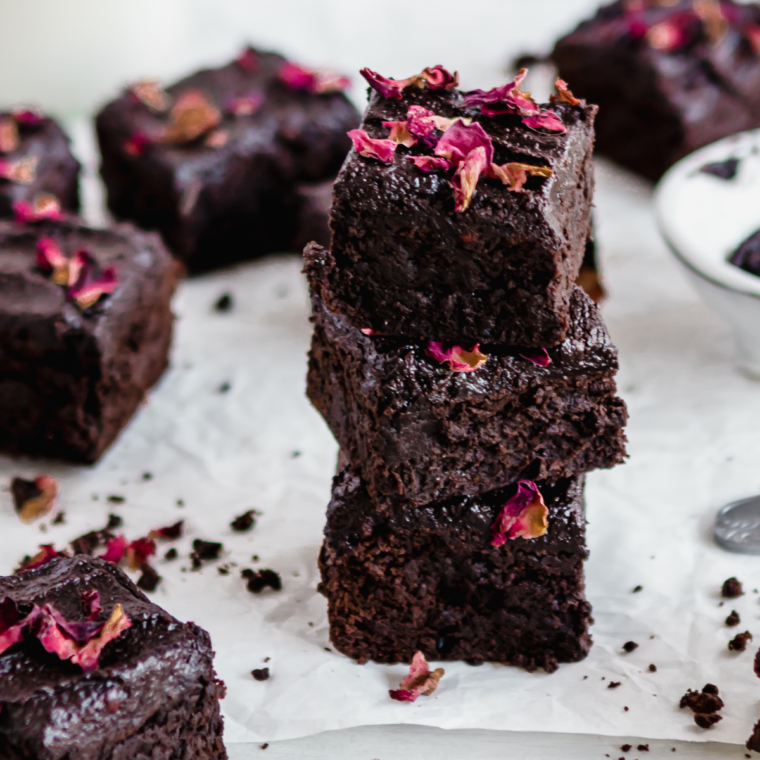 Zucchini brownies cut into squares and arranged on a sheet of white parchment paper.