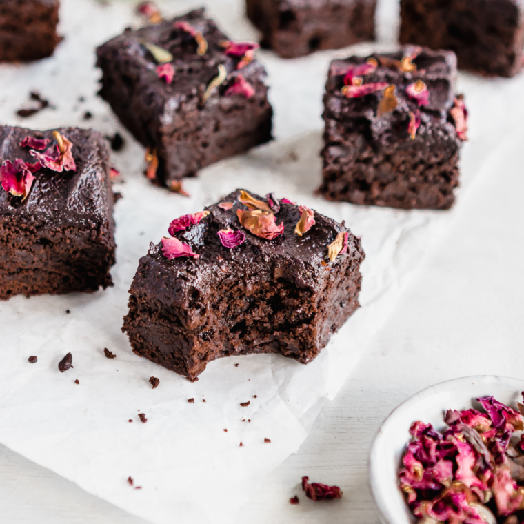 A batch of zucchini brownies displayed on a white parchment paper, showing their rich, chocolatey texture.