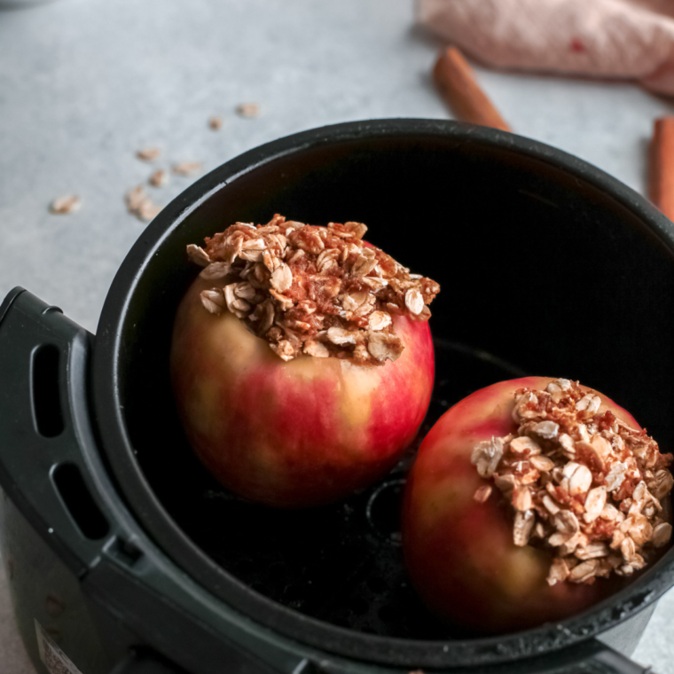 Stuffed apples placed upright in air fryer basket, cooking until tender and golden with caramelized filling.