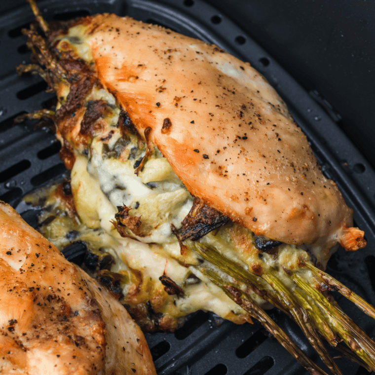 Instant-read thermometer in air fryer stuffed chicken showing 165°F internal temperature
