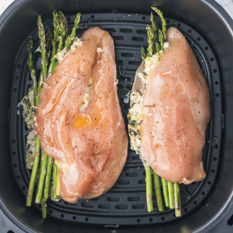 Stuffed chicken breasts arranged in a single layer inside the air fryer basket