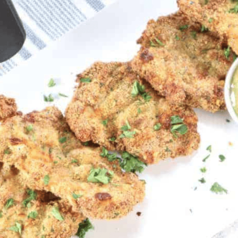 Crispy breaded chicken thigh schnitzel on a white plate made in the air fryer