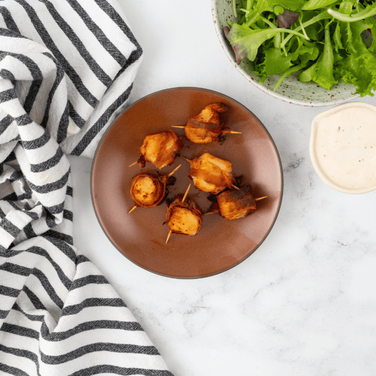 Air fryer-cooked frozen scallops wrapped in crispy bacon, golden and ready to serve.