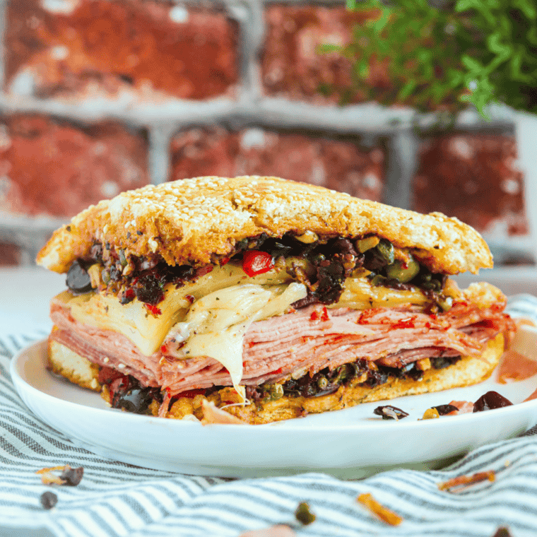 Close-up of a crispy Air Fryer Muffaletta Sandwich with layers of deli meats, cheese, and olive salad."