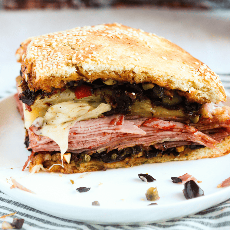 "Golden and crispy Air Fryer Muffaletta Sandwich with layers of salami, ham, provolone cheese, and tangy olive salad."