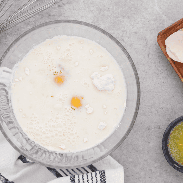 Air fryer preheating while flour, milk, eggs, salt, and melted butter are whisked into smooth, thin, pourable batter