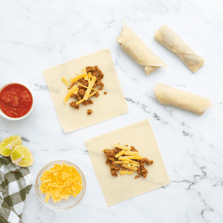 Filling wonton wrappers - A hand placing seasoned ground beef into wonton wrappers.
