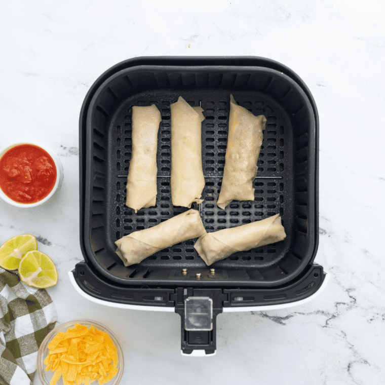 Placing wontons in the air fryer - Wontons arranged in a single layer in the air fryer basket.