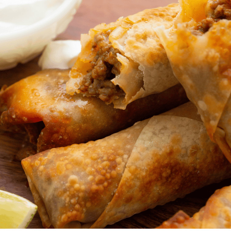 A plate of crispy Air Fryer Taco Bell Wontons, garnished with chopped green onions and served with a side of dipping sauce.
