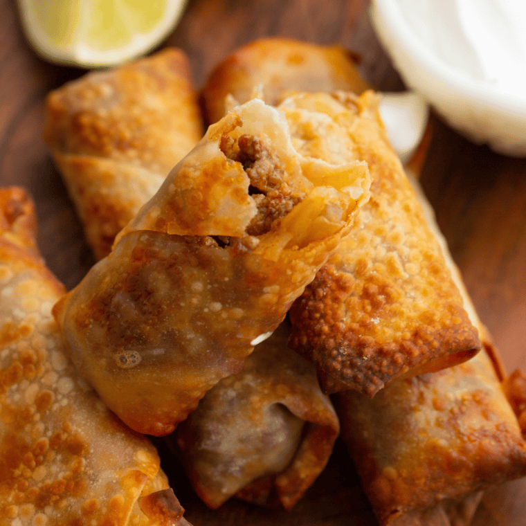 A plate of crispy Air Fryer Taco Bell Wontons filled with seasoned meat and topped with fresh garnishes.