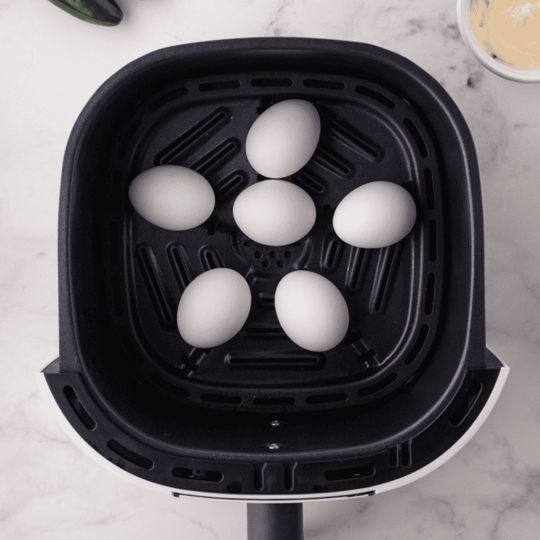 Six hard-boiled eggs cooling in an ice water bath before making deviled eggs