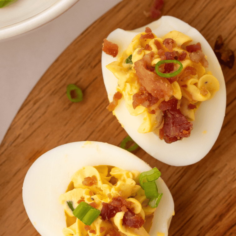 Million dollar deviled eggs on a serving plate garnished with paprika and fresh herbs