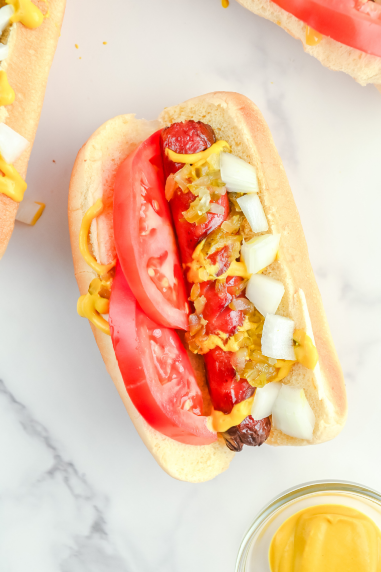 Chicago-style hot dog made in air fryer with poppy seed bun, mustard, relish, onion, tomato, pickle spear, sport peppers, and celery salt.