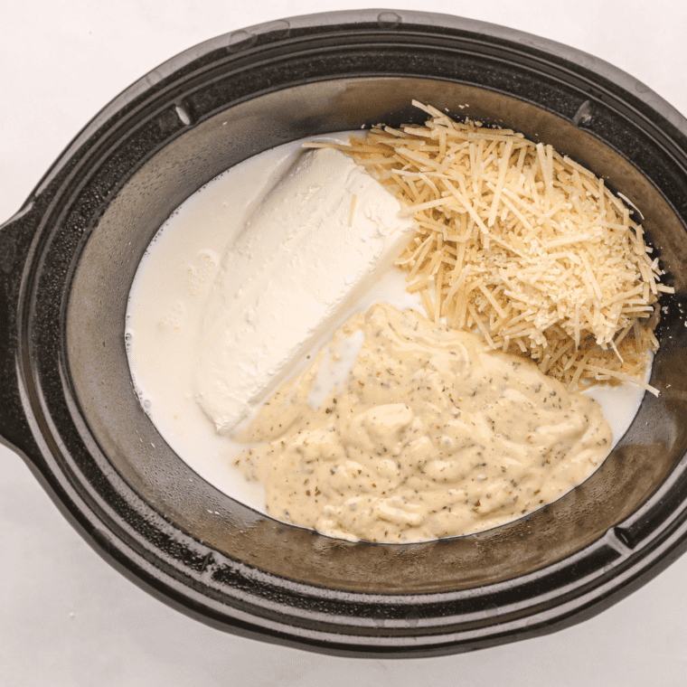 Raw chicken breasts and garlic parmesan sauce layered in a slow cooker