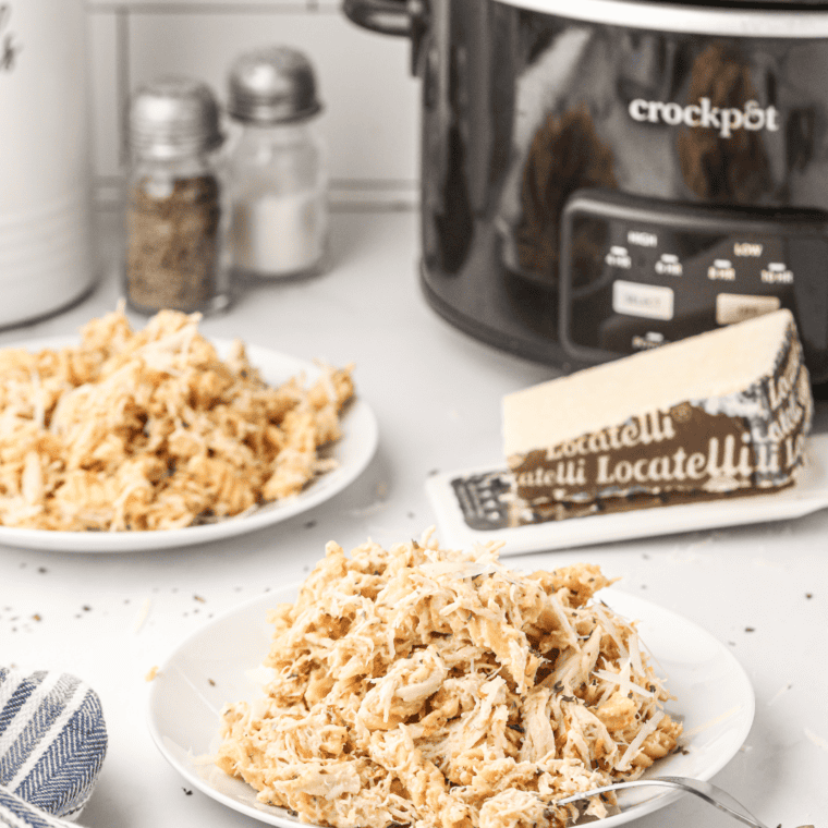 Juicy crockpot shredded chicken served in a white bowl.
