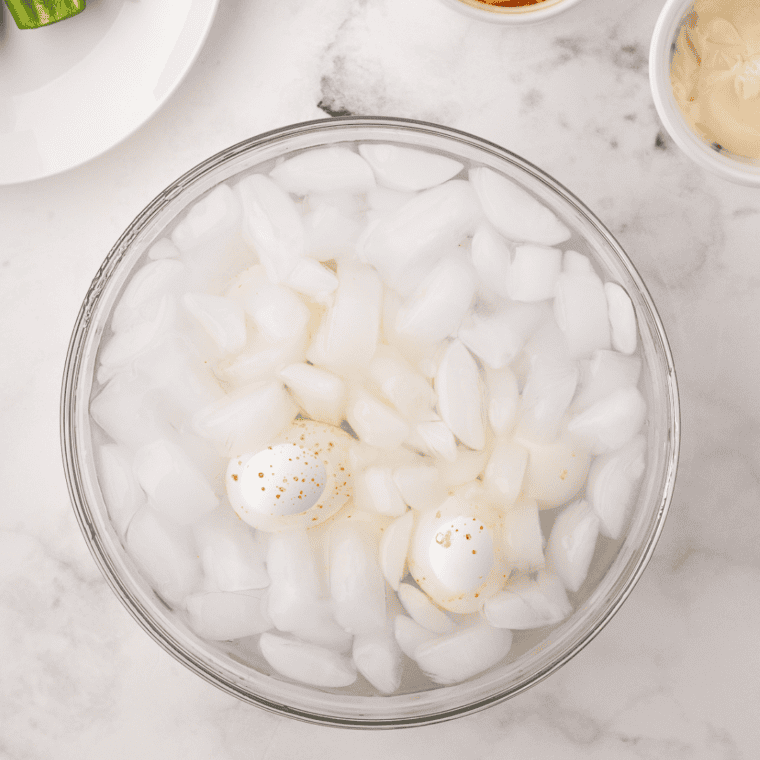 Hard boiled eggs cooling in a bowl of ice water before peeling