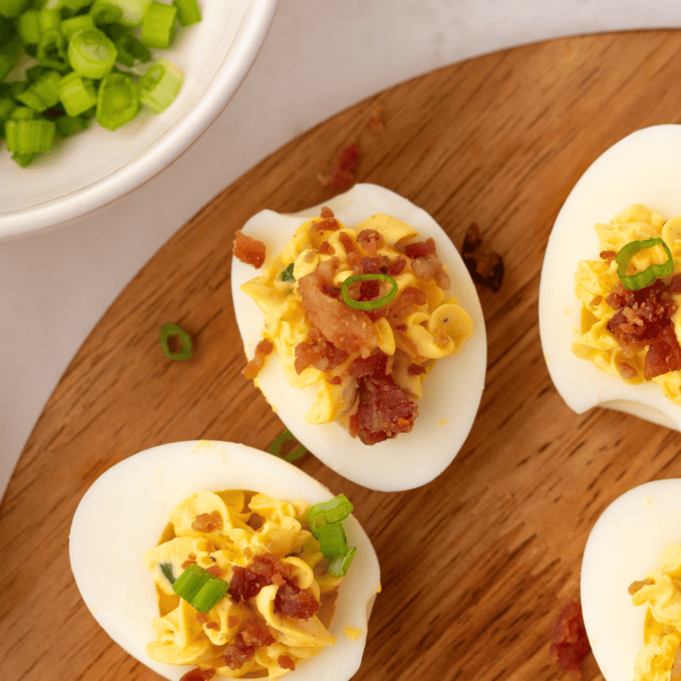 Finished bacon jalapeño deviled eggs with creamy filling, topped with fresh jalapeño slices and paprika