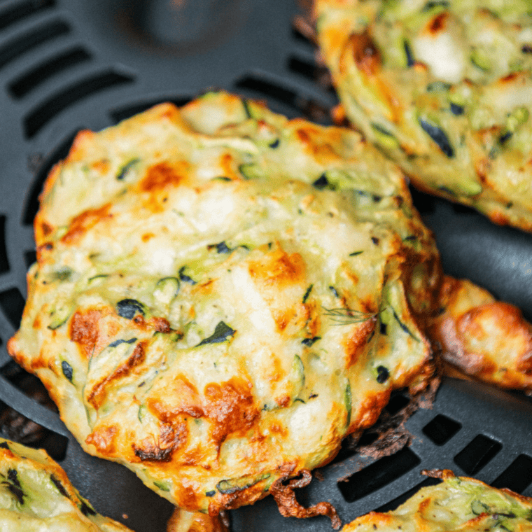 "Close-up of crispy Ninja Foodi Woodfire Zucchini Fritters with a dipping sauce on the side."