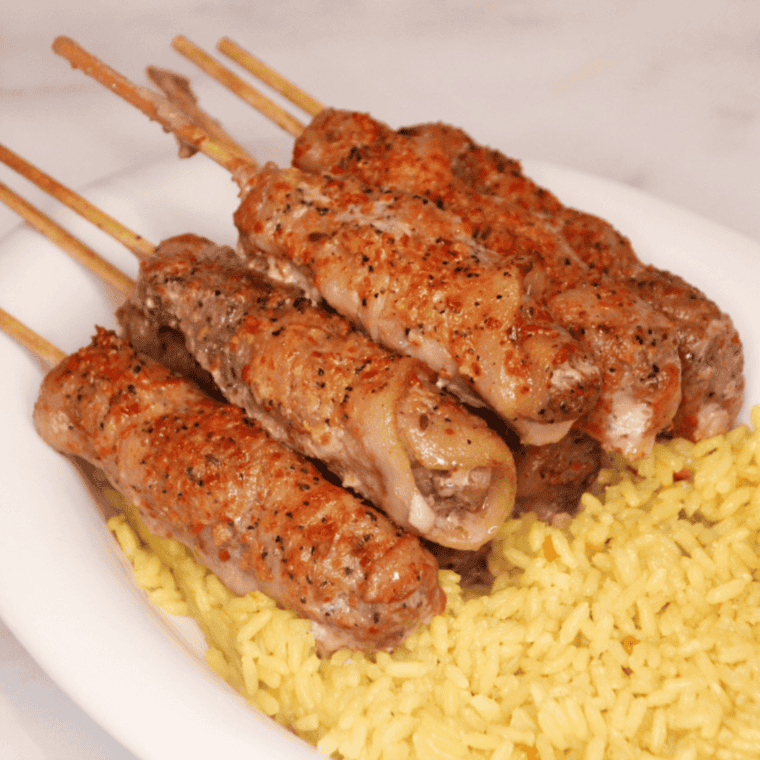 Air fryer bacon wrapped steak bites served on a plate with toothpicks for easy snacking.