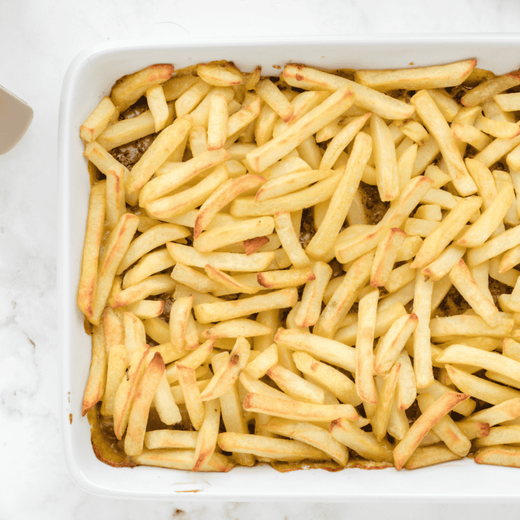 Frozen French fries arranged in a single layer over the beef mixture