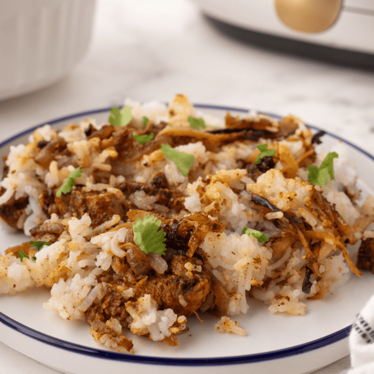 Golden air fryer chicken biryani with basmati rice, spices, and herbs served in a bowl.