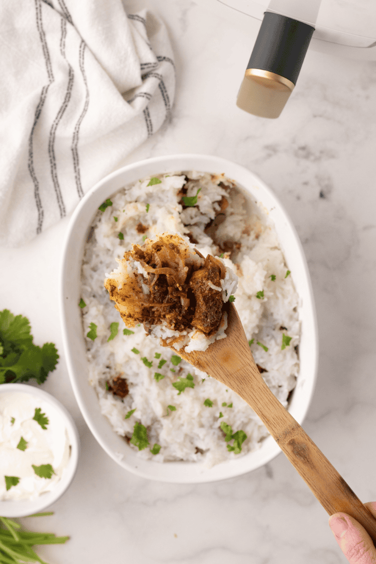 Air fryer chicken biryani with layers of spiced rice and marinated chicken, topped with herbs and fried onions.