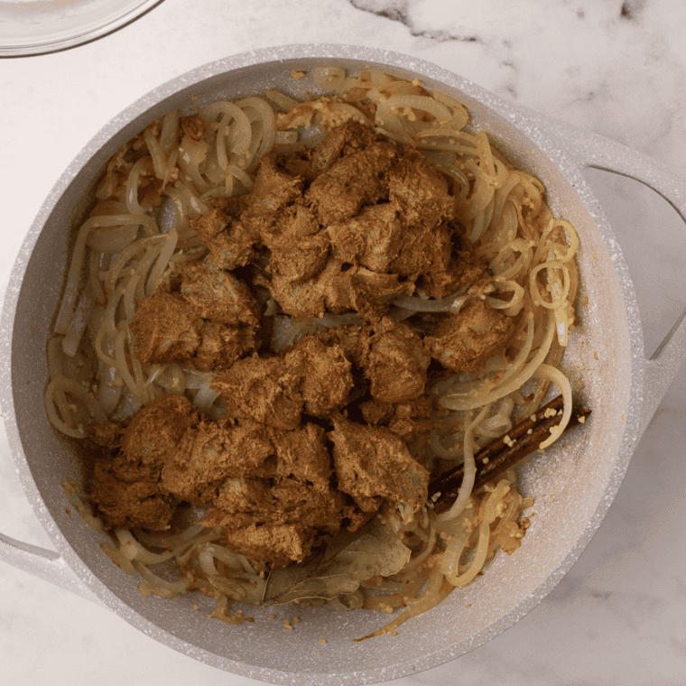 Partially cooked basmati rice in a pot with water, salt, and oil, preparing for layering with chicken.
