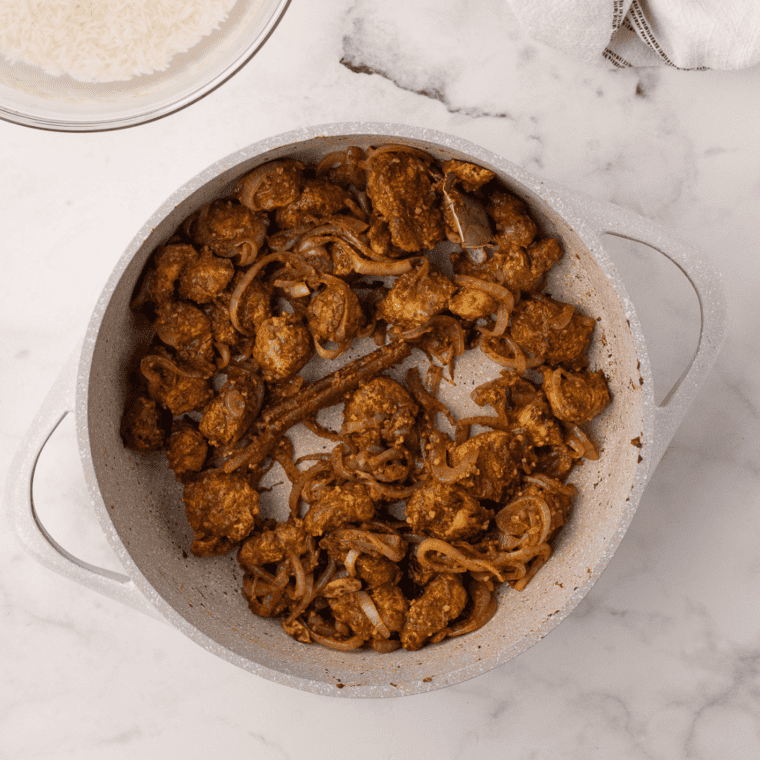 Layering rice and cooked chicken in a baking dish, topped with saffron milk for added color and fragrance.