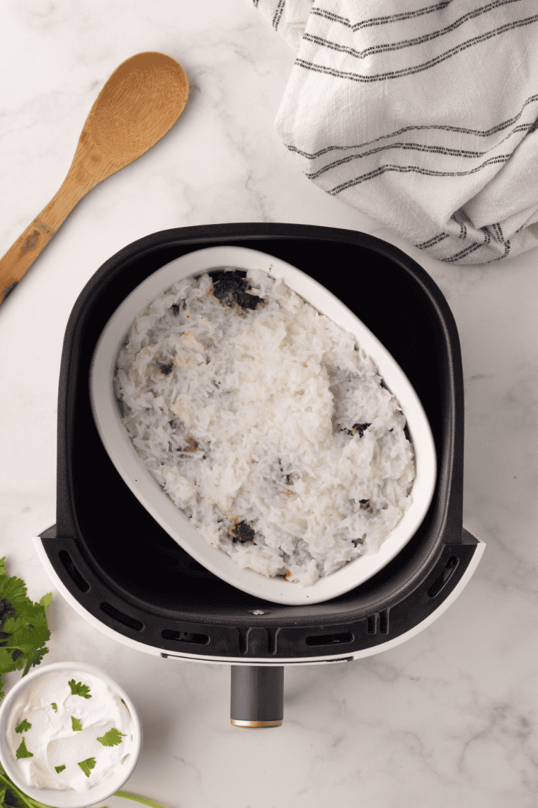 Layered chicken biryani with basmati rice and spices, cooked in the air fryer and garnished with herbs.