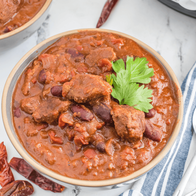 A vibrant dish of Air Fryer Chili Con Carne, showcasing a hearty mixture of ground beef, beans, and tomatoes, topped with fresh cilantro and served in a rustic bowl, with a side of crusty bread.