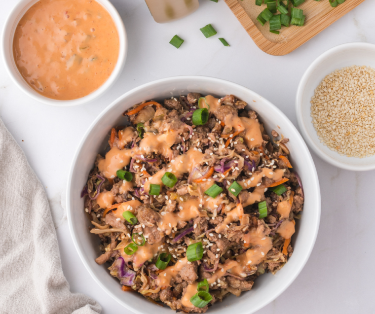 A close-up image of Air Fryer Egg Roll In A Bowl, featuring a colorful mix of stir-fried vegetables and ground meat, topped with sliced green onions and sesame seeds, all served in a rustic bowl.