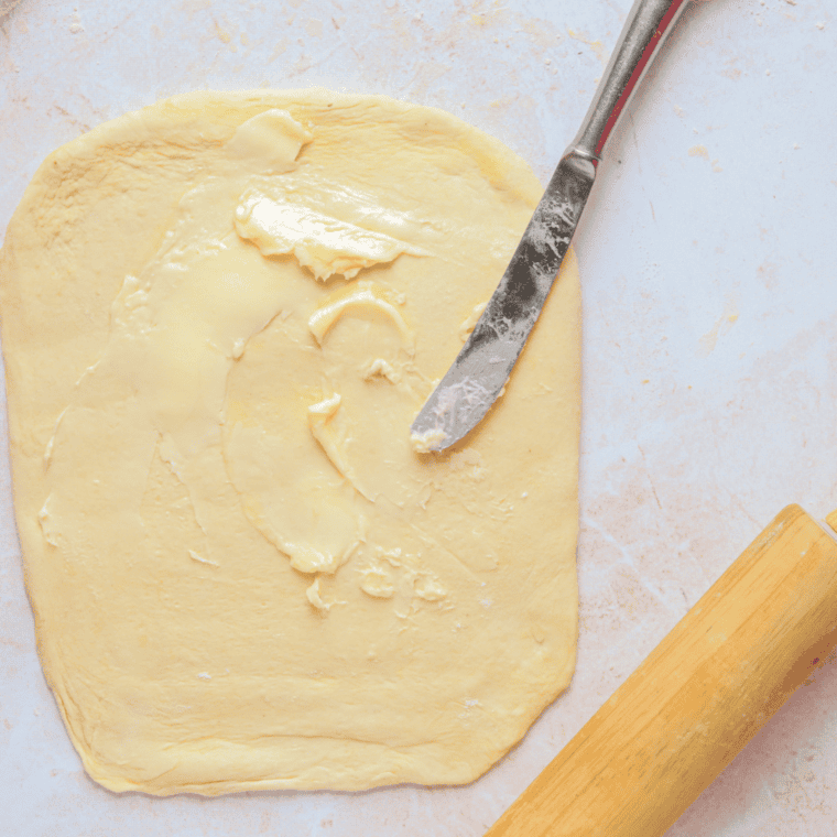 Rolling croissant dough thin, spreading butter, and folding into layers before chilling.