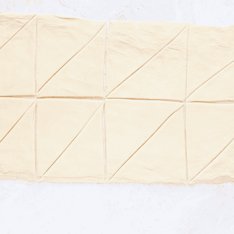 Brushing croissants with egg wash for a golden, glossy finish.