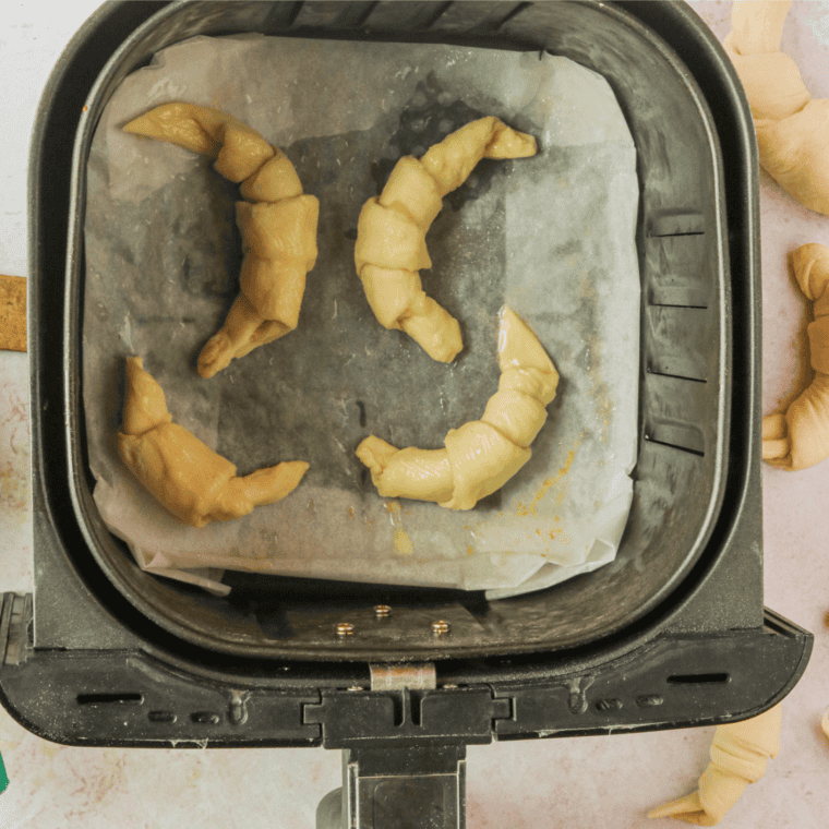 Arranging croissant dough in a single layer in the air fryer basket for baking.